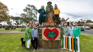 Loretta Gurnett (top left) stands with Koroit's spud-picker statue, adorned with a coat of crocheted shamrocks, and other members of the Country Women's Association who helped to create them. Picture by Anthony Brady
