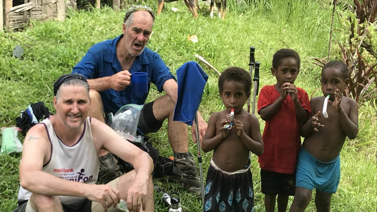 Walkers share their food with local children during a rest break on the Kokoda Trail.