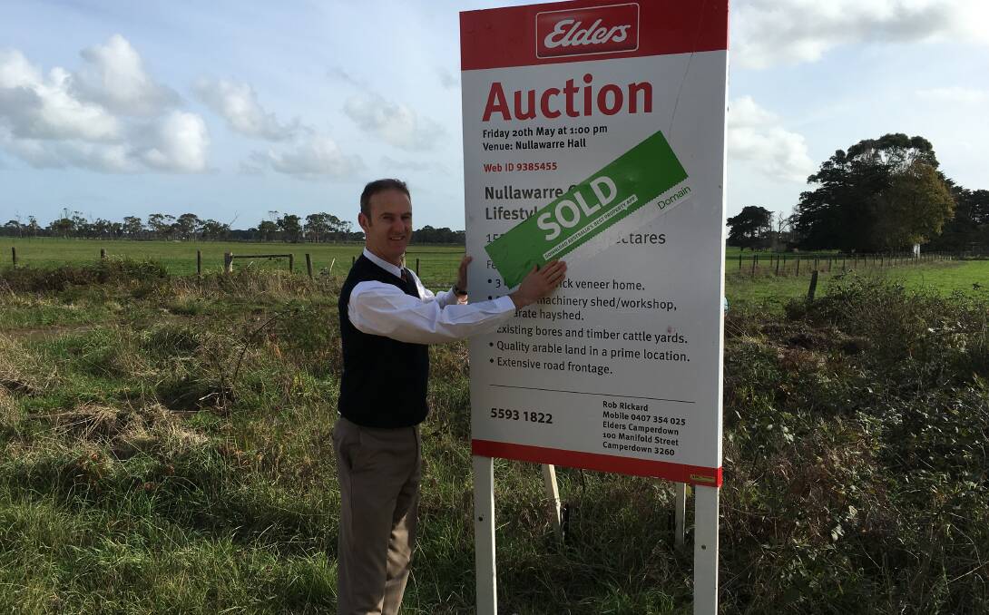 SUCCESS: Elders real estate agent Rob Rickard applies a sold sticker to an outpaddock at Nullawarre after it was auctioned. 