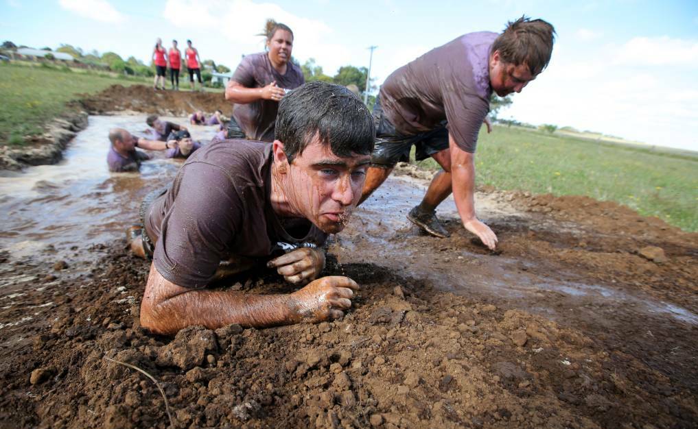 Cleansing: Aaron's Army team members crawl through the mud bath, one of the last Tower Hill challenges. Picture: Rob Gunstone