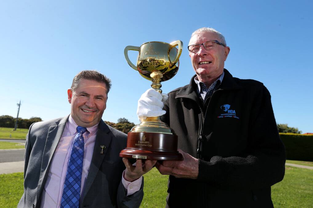Horse-mad: Melbourne Cup winning jockey Wayne Harris (1994 aboard Jeune), and Warrnambool RDA president Norm Halliwell hold up the 2016 Melbourne Cup, as the trophy visits Warrnambool. Picture: Rob Gunstone