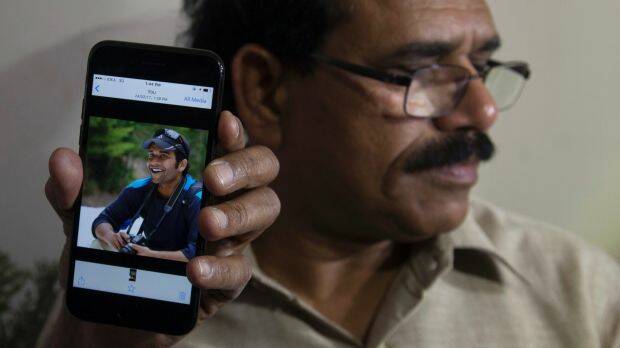 A man shows a picture of Alok Madasani, as his father Jaganmohan Reddy talks to the media in Hyderabad, India. Photo: AP