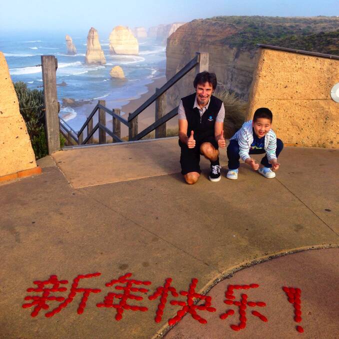 Thumbs up: a young Chinese boy helps Port Campbell Visitor Information Centre co-ordinator Mark Cuthell with Chinese characters spelling 'happy new year!' at the Twelve Apostles.
