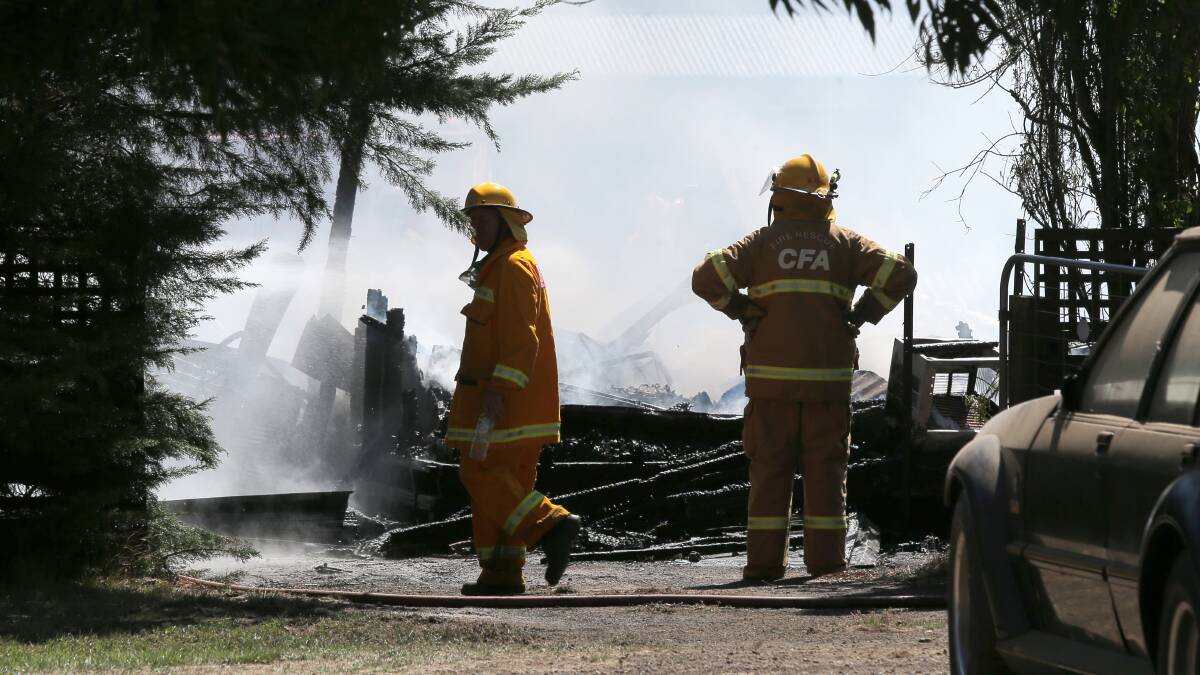 CFA officers work to cool the remains of a house that burnt down in Hawksdale. Picture: Rob Gunstone