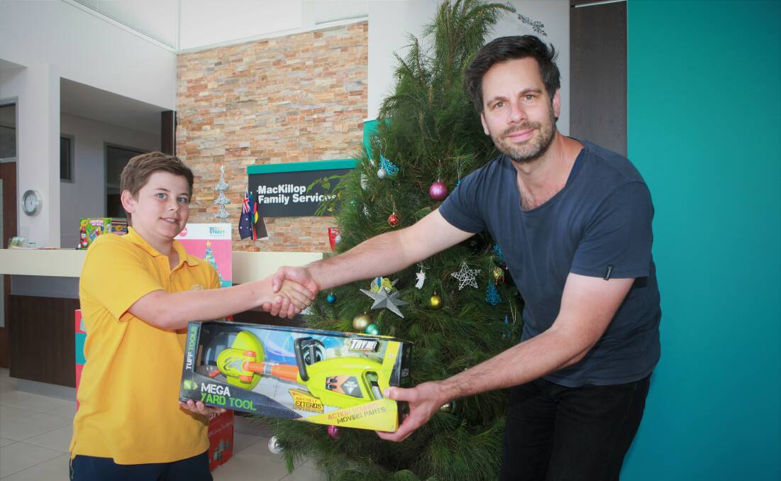 HELPING HAND: MacKillop Family Services area manager Cameron Burgess accepts a donation from Cooper Ferris. Picture: Anthony Brady