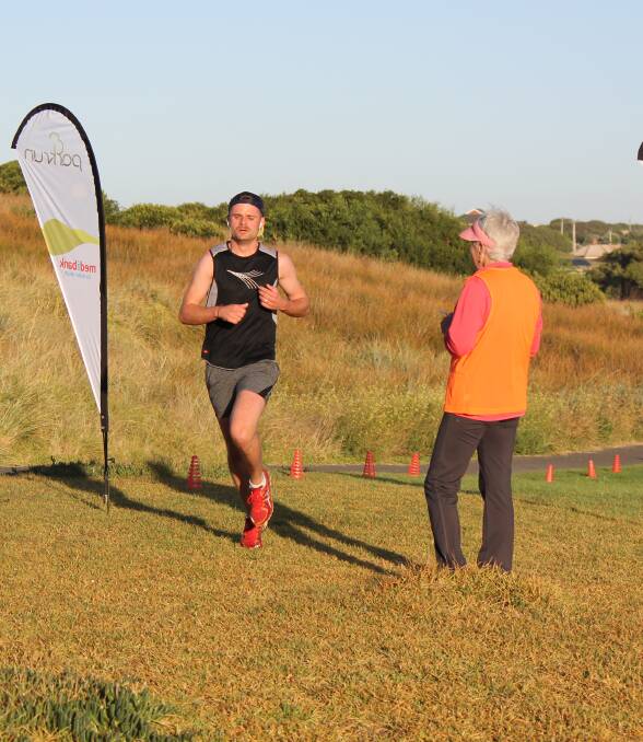Help wanted: Parkrun participant James Chapman crosses the finish line while volunteer Debbie Sheehan watches on. More volunteers are needed for the event which is held each Saturday at Russell Clark Reserve, Port Fairy.
