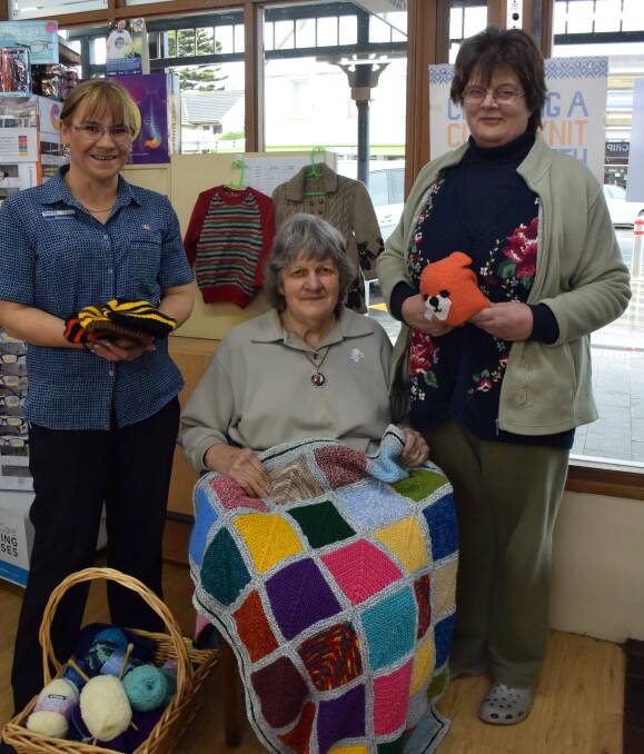 Made with love: McLean's Pharmacy retail manager Gwenda Wilson with Port Fairy knitters Marj Young and Debbie Young (standing). Picture: Madeleine McNeil