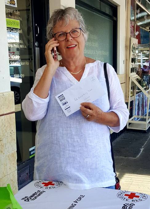 Prize: Port Fairy Red Cross member Judi Handby on the phone to Judy Roberts who won a family ticket to the Port Fairy Folk Festival. 