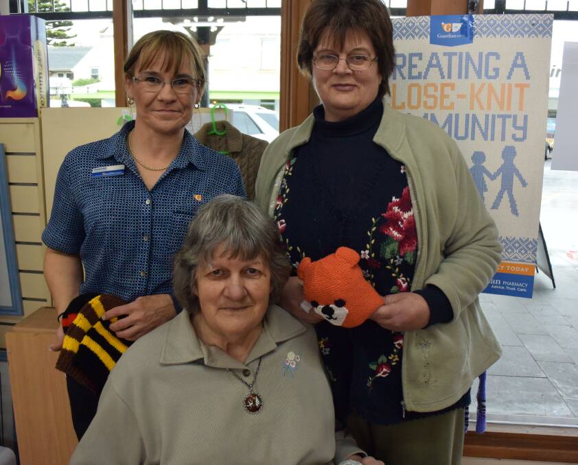 Made with love: McLean's Pharmacy retail manager Gwenda Wilson with Port Fairy knitters  Debbie Young (back) and Marj Young. Picture: Madeleine McNeil