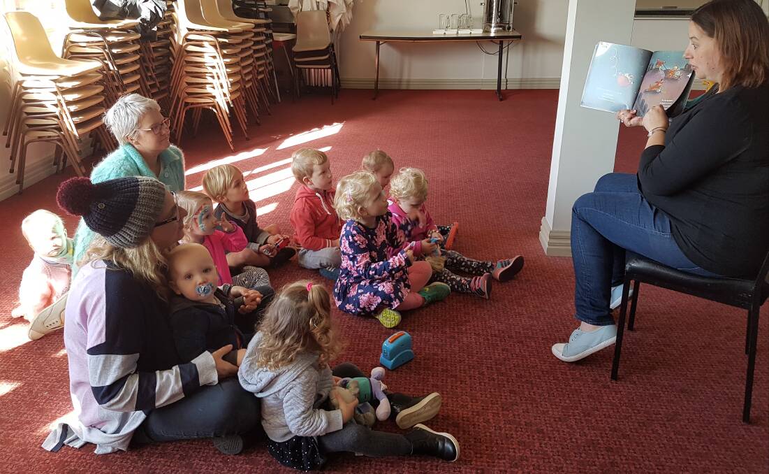 Engrossed: Parent Kirri Nield reads The Cow Tripped Over the Moon to Port Fairy Playgroup members on Wednesday as part of National Simultaneous Storytime. 
