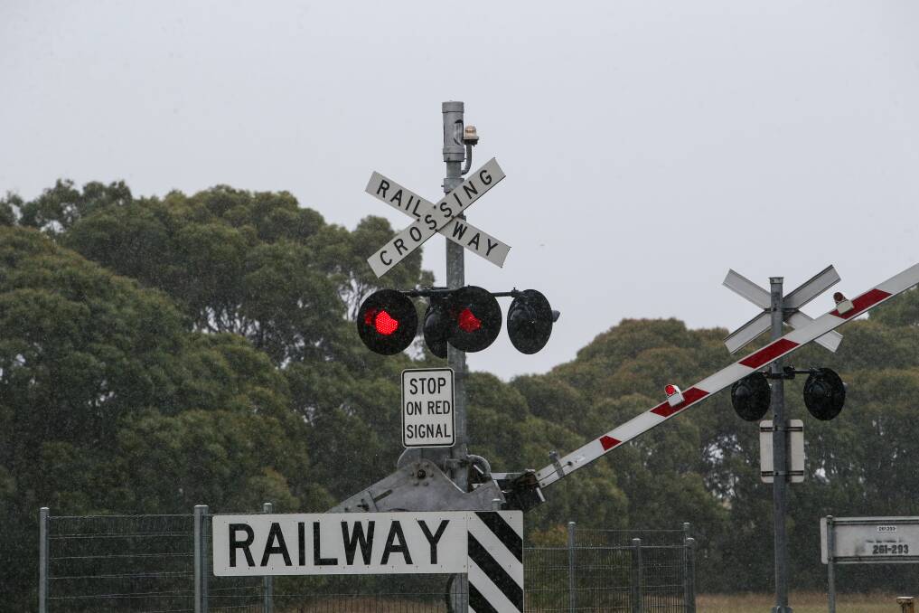 Boom gates lowering and lights flashing at a Warrnambool level crossing to signal a train on its way.