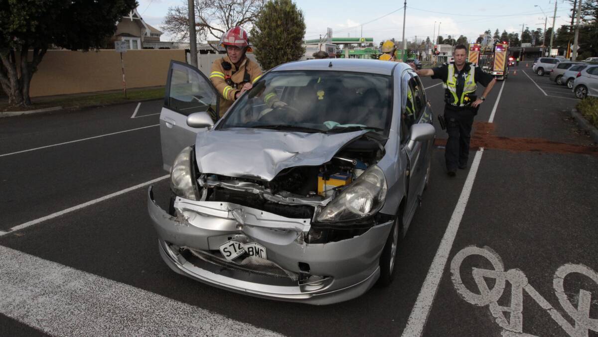 Police and firefighters push the damaged Honda off Jamieson Street, Warrnambool, after it was involved in accident in which an 11-year-old boy was injured. 