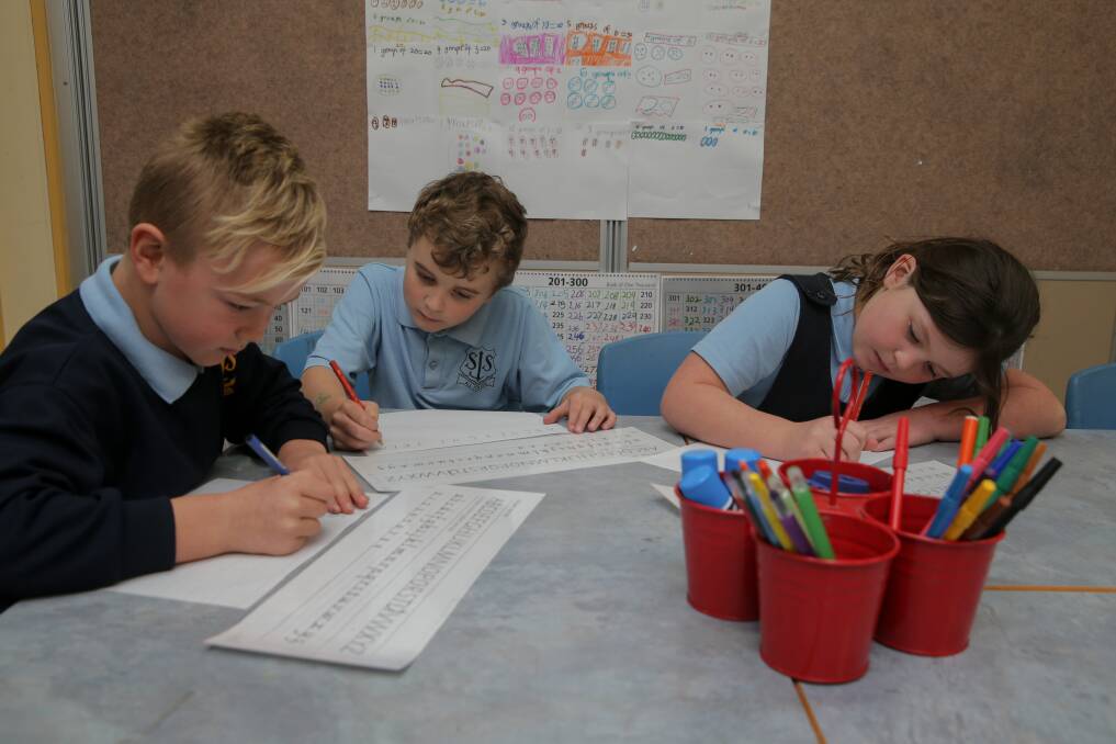 Pen and paper: Warrnambool St Josephs Primary students Billy Schrama, 7, Jacob Ward, 8, and Edith Walsh are continuing in learning basics. Picture: Rob Gunstone