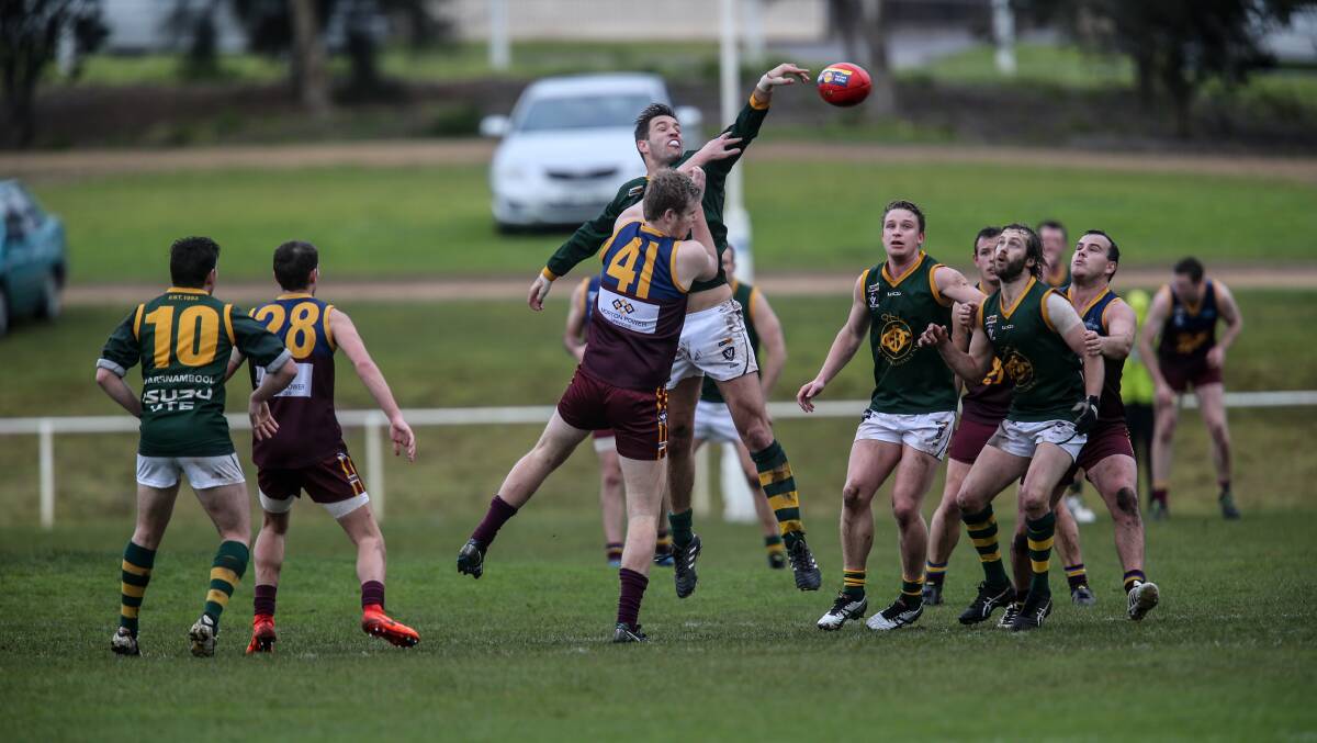 HIGH LEAP: Old Collegians # 62 Scott Lenehan taps away the ball. Picture: Christine Ansorge