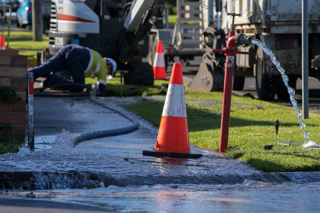 DOWN THE DRAIN: A worker tries to stem the water flow from a burst main at the intersection of Simpson St and Bostock St on Sunday. Picture: Rob Gunstone