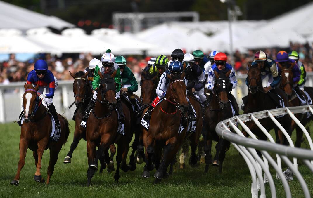 AROUND THE BEND: The field gallops into the first turn before Boom Time won the Caulfield Cup at Caulfield racecourse in Melbourne on Saturday. Picture: AAP 