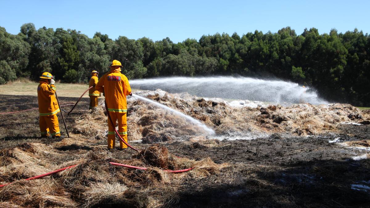 Under control: CFA crews spray hay bales that burnt in the Cudgee fire that threatened two houses on Esterly Ridge Road. 