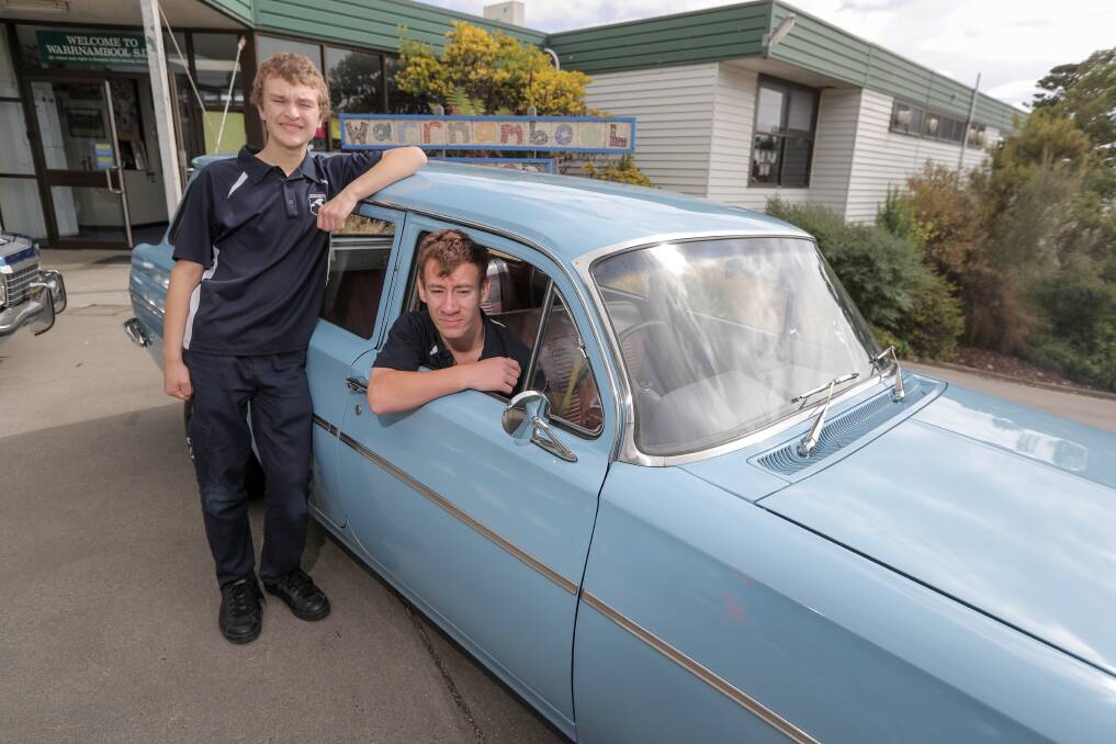 Warrnambool SDS students James Clisby, 15, and Paul Torney, 15, rest out one of the classic Holdens that will be on display at Lake Pertobe on Saturday. Picture: Rob Gunstone