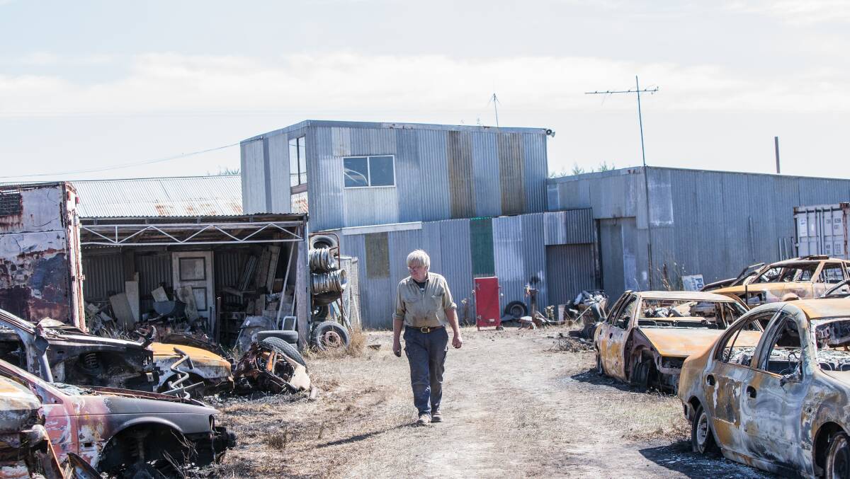 Confronting: Neil Podger walks among the burnt out wrecks of cars, many of which exploded in the intense heat of Saturday night's fire. 