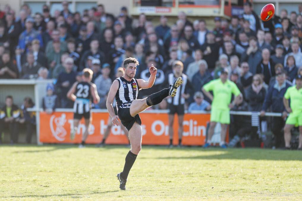 A large crowd watches on as Will Rowbottom kicks for goal in the 2018 Hampden league grand final between Camperdown and Koroit. File picture 