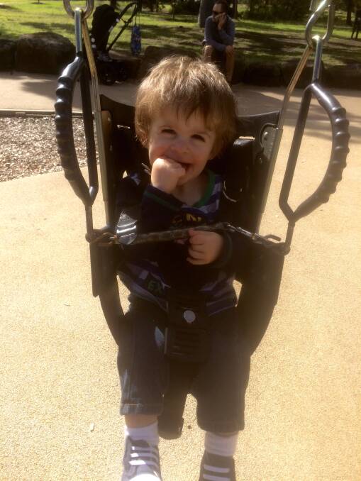 Marshall Hayhoe, 2, enjoys at trip to an all-abilities playground in Melbourne. His parents are hoping to get a swing like this installed in Warrnambool.