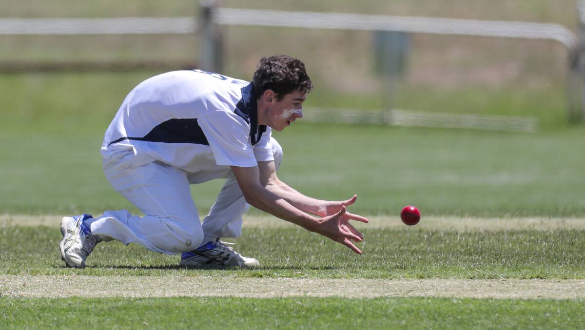 STAR EFFORT:  Warrnambool bowler Nick Robertson tries to get his fingers under a low catch from his own bowling. He snared six wickets.