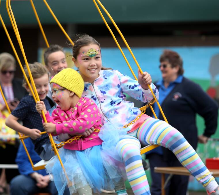 A Spring swing: Kryschelle, 3, and Eyesha Kelly, 9 from Purnim, hang on tight as they spin round and round on one of the rides offered. Picture: Amy Paton