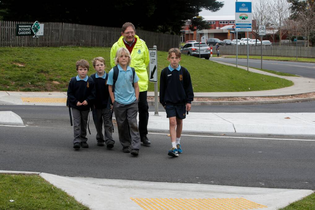 St Joseph's Primary School principal Michael Gray helps students Trae Brereton, Cale Brereton, Nate Brereton and Kye Brereton to cross the intersection attracting proposed changes.

