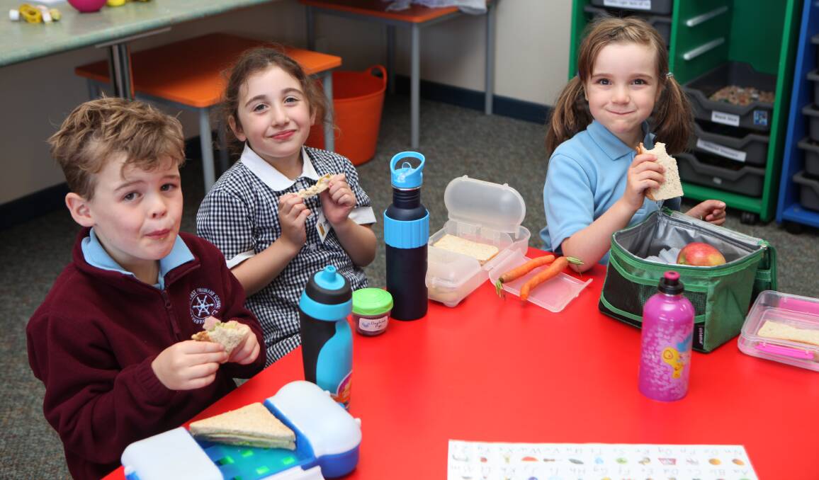 Calm before the storm: Warrnambool East Primary School foundation students Darcy McLeod, 5, Daphne Pye, 6 and Sophia Walter, 5 are filling up on an earlier break before heading outside for 'outdoor play'. Picture: Rebecca Riddle.