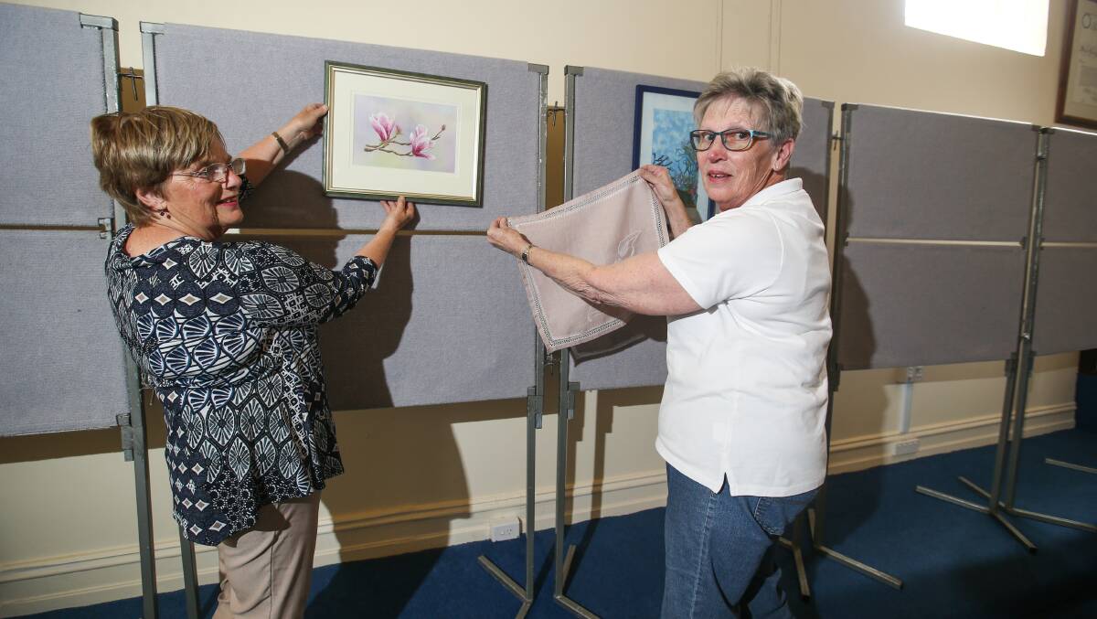 The south-west branch of the Embroiderers Guild Victoria convenor Lorraine Blackmore and exhibition committee member Judy Miller hanging two of the pieces set to be on show this weekend. Picture: Amy Paton