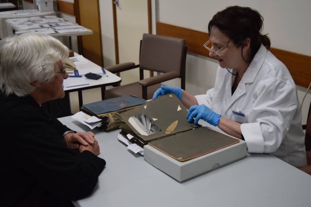 Close inspection: University of Melbourne paintings conservator Caroline Fry inspects a historical artefact. Next month experts will travel to Warrnambool for a war heritage roadshow. Picture: Courtesy of the University of Melbourne