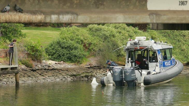 A child looks on as police retrieve another suspicious object from the river in February. Photo: Chris Hopkins