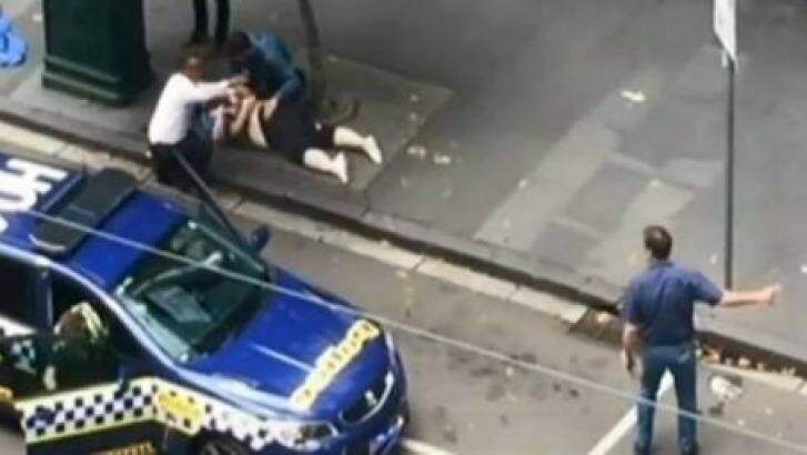 An image of Henry Dow and taxi driver Lou caring for a victim of the Bourke Street attack on Friday. Photo: Seven News Melbourne