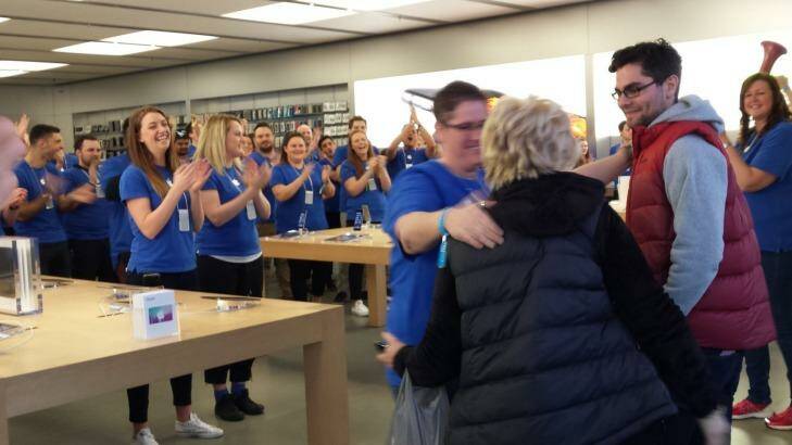 David Brown, first in line at Chadstone, gets a hug from Apple staff as doors opened. Photo: Larrisa Nicholson