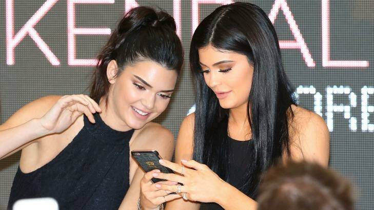 Kendall Jenner and Kylie Jenner look at their mobile phones as they arrive at Chadstone. Photo: Scott Barbour