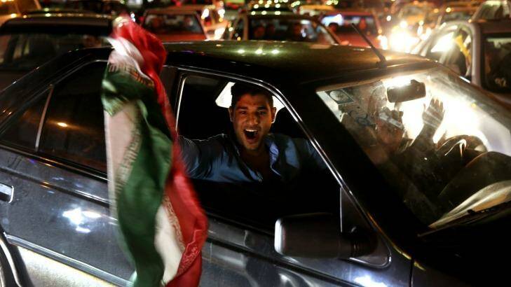 An Iranian waves his country's flag while celebrating on a street in northern Tehran after Iran's nuclear agreement with world powers in Lausanne, Switzerland.  Photo: Ebrahim Noroozi