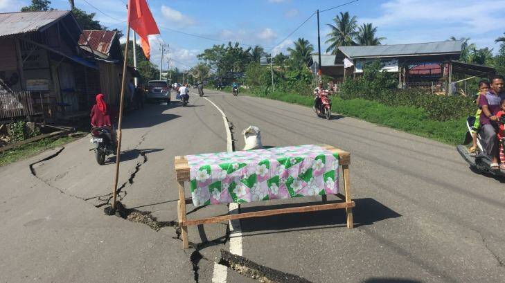 A table and flag warn motorists of cracks in the road in Trienggadang, Aceh. Photo: Jewel Topsfield
