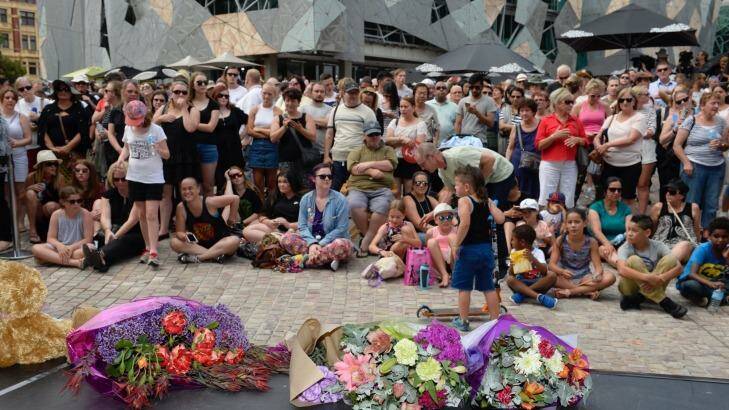 Mourners and flowers at Federation Square.
