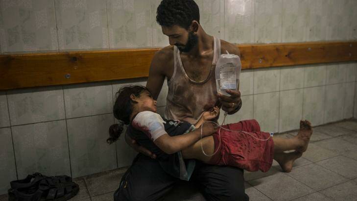 Mohammed Shinbary comforts his daughter Mahasin, 7, who was injured after an attack on a United Nations school. Photo: New York Times