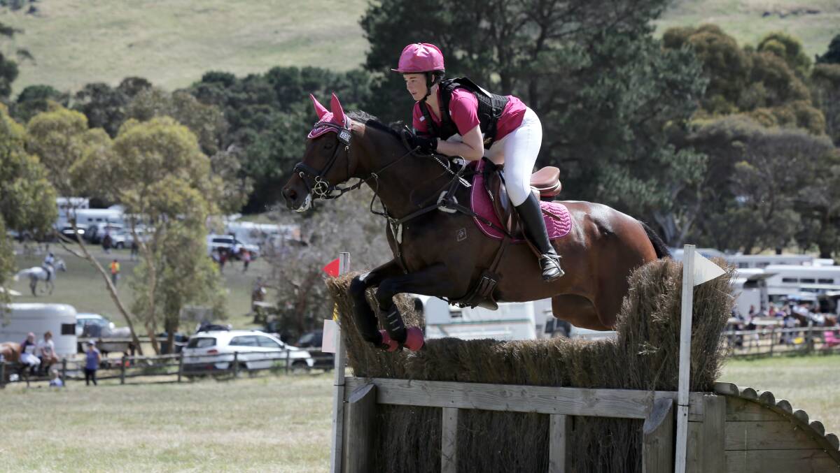 Rebecca McCrae, with Hi Tide, clears the brush jump as part of the cross-country course. 