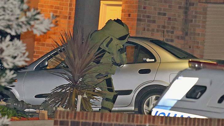 A police officer in bomb suit inspects the car at the scene. Photo: Getty Images/Scott Barbour