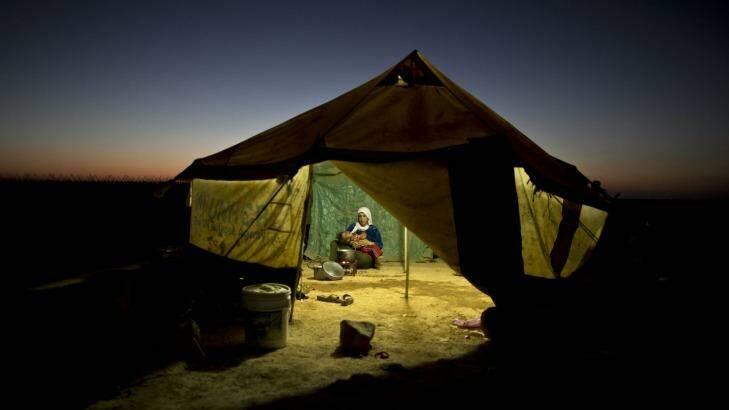 A Syrian refugee woman tends to her daughter while cooking inside her tent at an informal tented settlement near the Syrian border on the outskirts of Mafraq, Jordan, in August 2015. (AP Photo/Muhammed Muheisen)