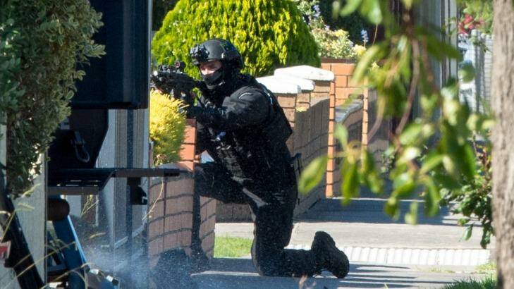 An armed officer takes up position outside the house. Photo: Penny Stephens