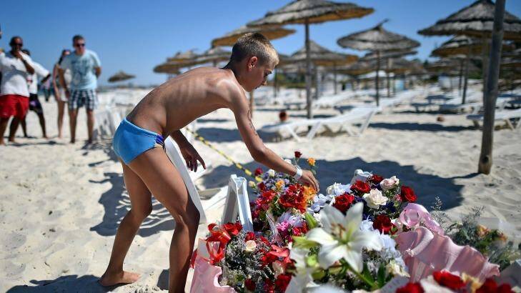 A boy leaves flowers at a memorial on the Tunisian beach where the attack took place. Photo: Jeff J Mitchell