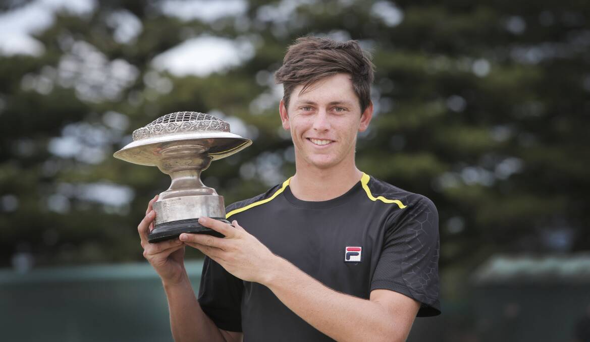 Men’s singles champion Andrew Whittington holds the spoils of victory at Warrnambool Lawn Tennis Club yesterday.