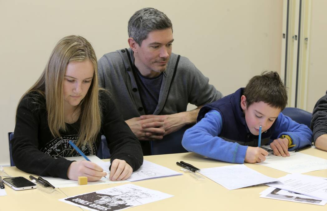 Young comic artists Emily Hogan, 14, of Warrnambool, and Lucas Kyle, 11, of Hamilton, learn new skills from local artist Gareth Colliton.  Picture: ROB GUNSTONE