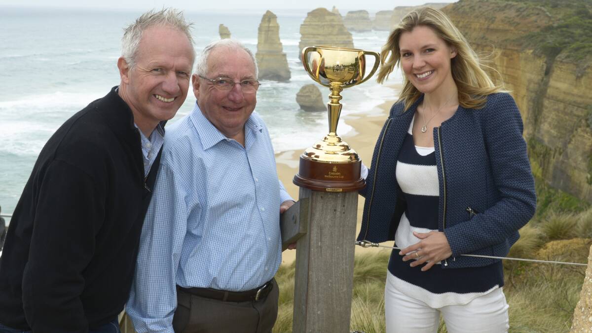 Victoria Racing Club tour manager Joe McGrath, left, former Melbourne Cup-winning trainer Mick Robins and public relations manager Julie Henkel show off this year’s cup at the Twelve Apostles yesterday. 