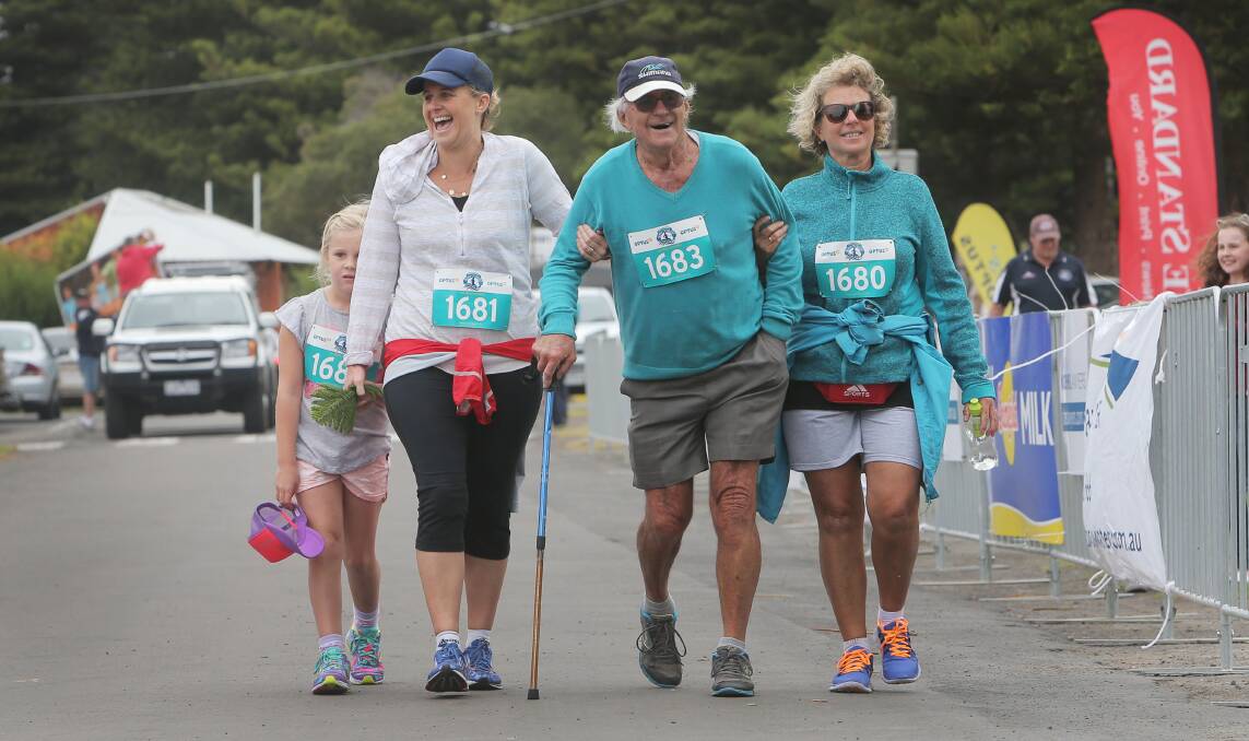 Family members Layla McCarthy (left), 6, Nicole McCarthy and Lauren King help Ron McCorkell reach the finish of the Surf ‘T’ Surf walk yesterday in Warrnambool.