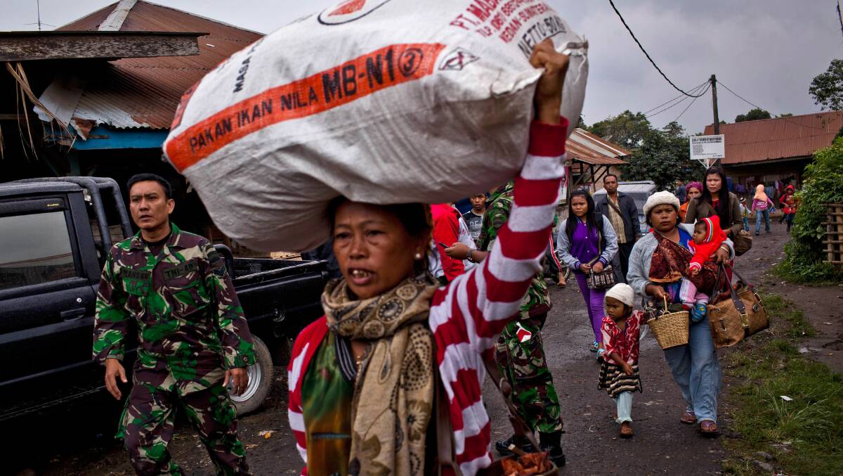 Villagers carry belongings as they evacuate to a temporary evacuation center following another eruption at Mount Sinabung in Pintu Besi village on January 3, 2014 in North Sumatra, Indonesia. Picture: Getty