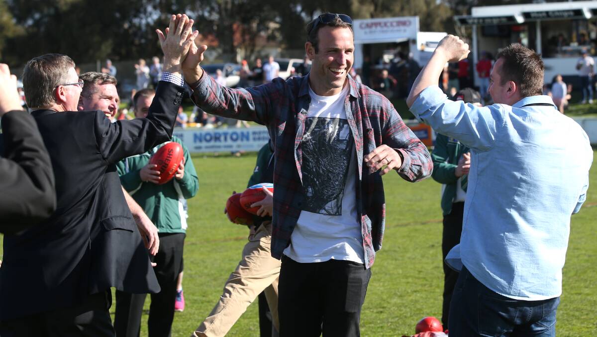 Former AFL star Brad Ottens high-fives Premier Denis Napthine after his success in winning $5000 for kicking the ball into the back of a ute.